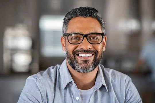 Professional portrait of a smiling man with gray hair, beard, and glasses, symbolizing an experienced Senior Business Professional at Ace Amaze.