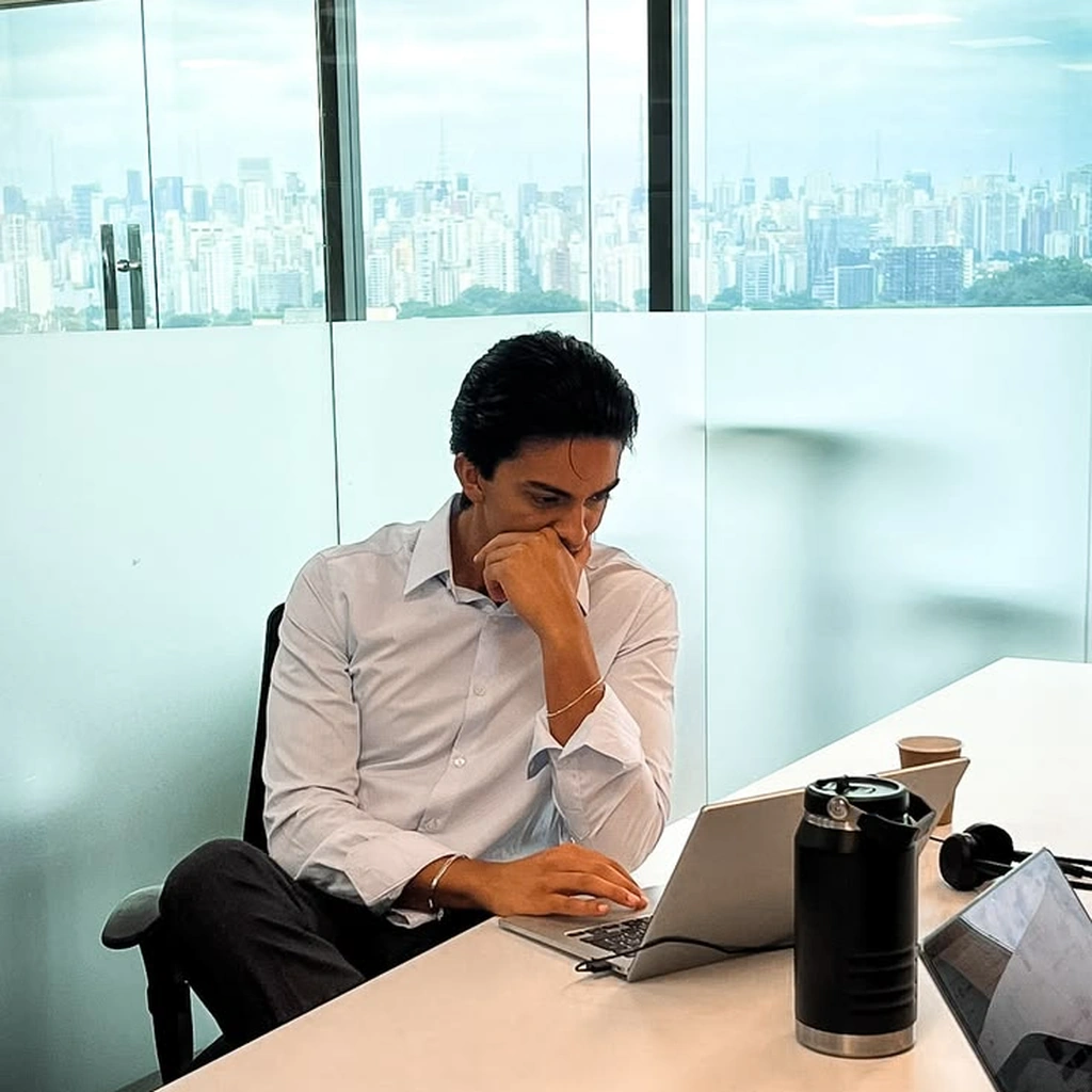 A professional working intently on a laptop at a desk in a high-rise office with a cityscape view, representing dedicated client management by a digital marketing company for Dehradun
